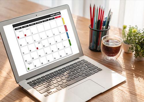Open laptop sitting on a desk with a monthly calendar showing